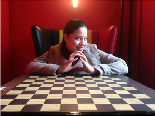 Ada sitting in a Belgian lounge chair with a chess board.